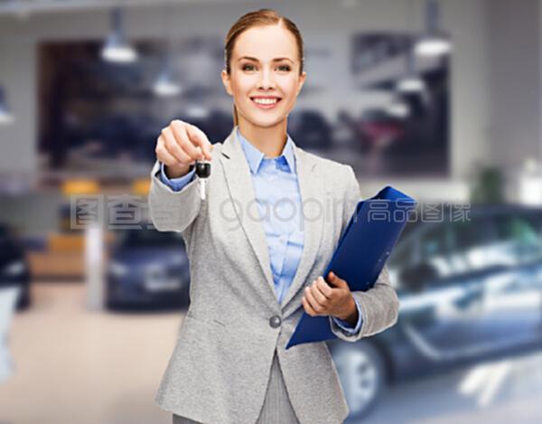 汽車業務,汽車銷售,手勢和人的概念-快樂的女商人或售貨員與文件夾給車鑰匙在汽車展示背景
